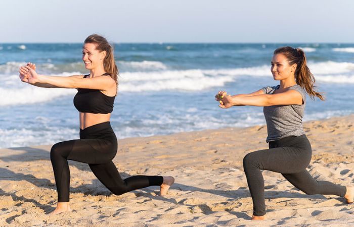 Zwei Frauen am Strand, die Yoga praktizieren.