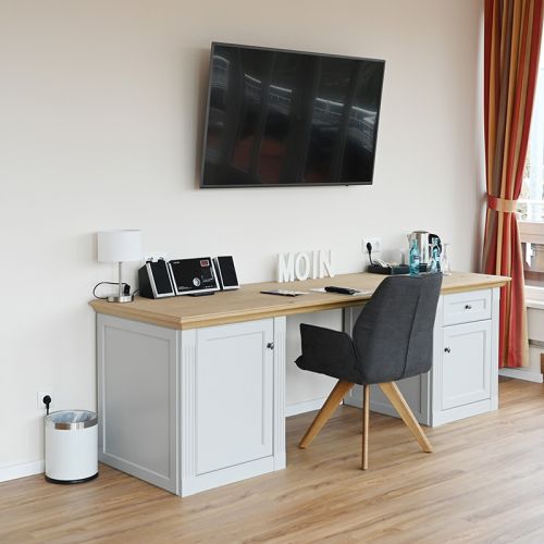 Schreibtisch mit Stuhl und Minibar in der Ostsee-Suite, auf dem Schreibtisch Welcome Tray Kaffee/Tee, Wasserkocher, Radio, neben dem Schreibtisch steht ein Papierkorb