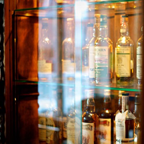 Whiskeylounge Hotel Hohe Wacht, Nahaufnahme Schrank mit Glasfronten, in dem Schrank verschiedenste Sorten Whiskeyflaschen