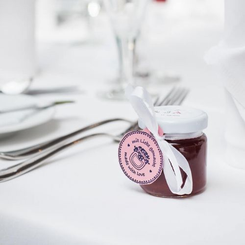 Nahaufnahme eingedeckter Tisch zur Hochzeitsfeier im Hotel Hohe Wacht, im Vordergrund Gastgebergeschenk kleines Marmeladenglas mit Etikett und Schleife für die Gäste