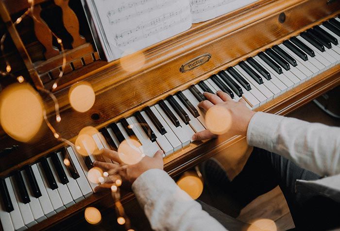 Hände spielen Klavier, davor eine Lichterkette
