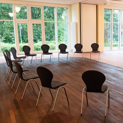 Tagungsraum Holstein im Hotel Hohe Wacht, halber Stuhlkreis, an der Decke Kronleuchter, helle Fensterfront