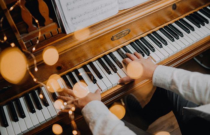 Hände spielen Klavier, davor eine Lichterkette