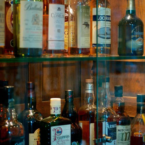Whiskeylounge Hotel Hohe Wacht, Nahaufnahme Schrank mit Glasfronten, in dem Schrank verschiedenste Sorten Whiskeyflaschen