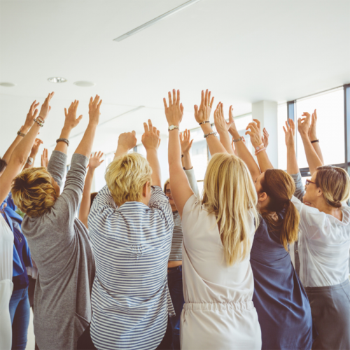 Gruppe von Personen, die ihre Arme hochstrecken, Rückenansicht