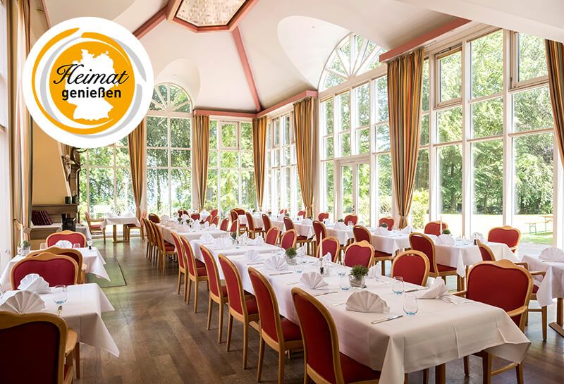 gedeckte Tafeln im Parkrestaurant, mit Teller, Besteck, Wassergläser, Kerzen, gefaltete Servietten, helle Fensterfronten mit Blick in den Kurpark, links oben im Bild Logo Heimat genießen