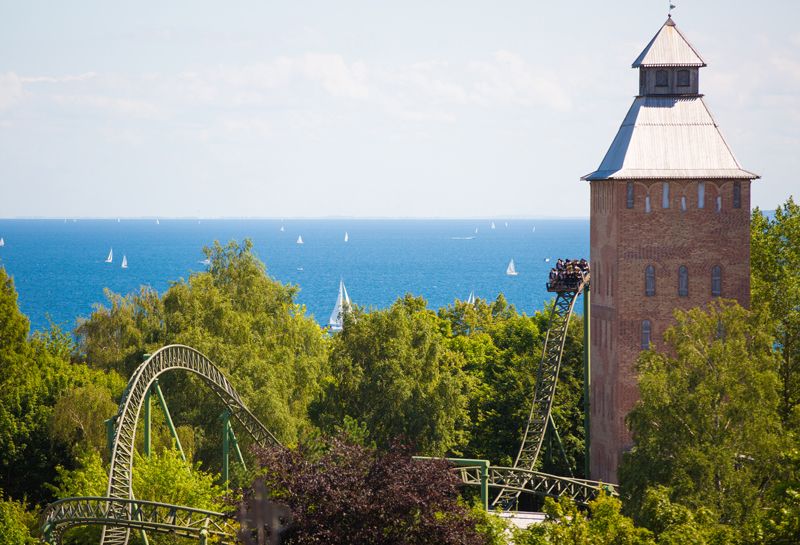 Aktivitäten Hotel Hohe Wacht, Attraktion Flucht von Novgorod im Hansa Park, Attraktion inmitten von grünen Bäumen, im Hintergrund Blick auf Ostsee mit vielen Segelschiffen