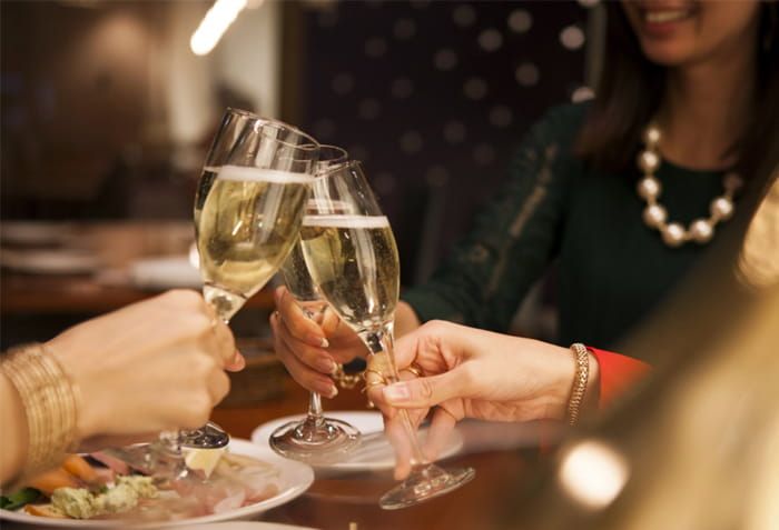 Zwei Frauen stoßen im Restaurant mit Champagnergläsern an