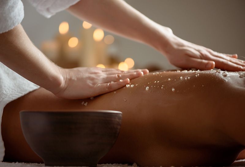 Massageklassiker Hohe Wacht, Person mit nacktem Oberkörper auf dem Bauch liegend, massierende Hände, Massage Peeling