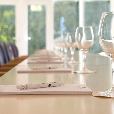 Tagungsraum Hotel Hohe Wacht, Nahaufnahme Tisch eingedeckt mit Schreiblöcken, Kugelschreiber und Trinkgläsern, Hintergrund Fenster