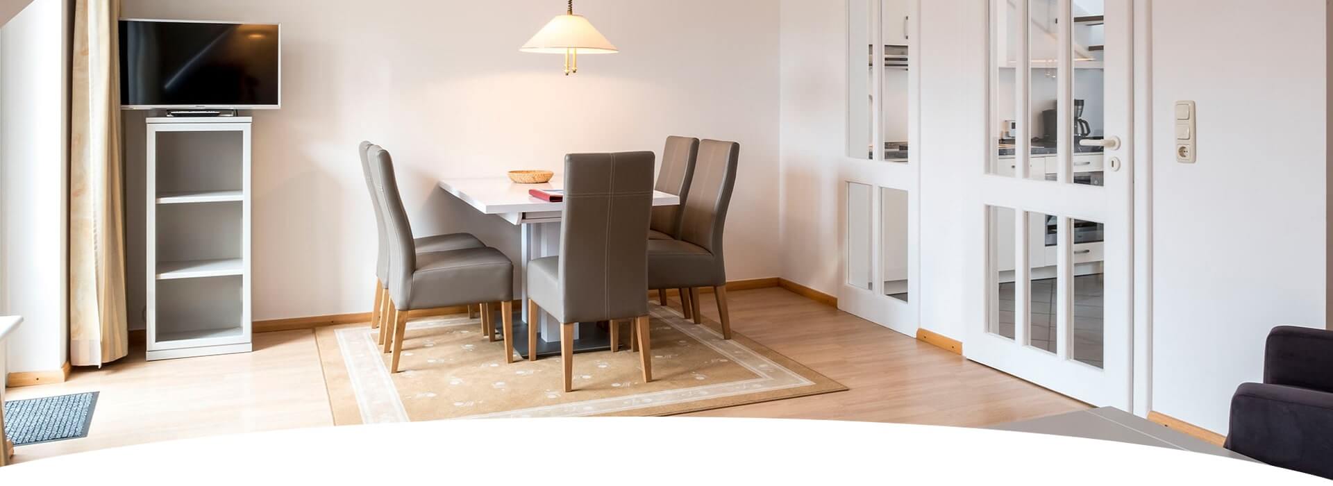 Hotel Hohe Wacht Appartment Wohnzimmer mit großem Tisch und Stühlen